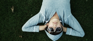 person laying on ground in hoodie and sunglasses