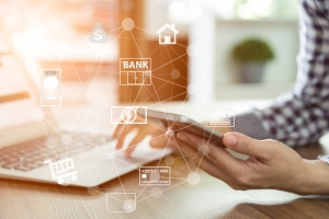 close-up-of-person-holding-smartphone-near-laptop-with-digital-overlay-of-payment-network-icons