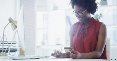 woman-wearing-red-sleeveless-shirt-holding-credit-card-at-counter-of-small-business