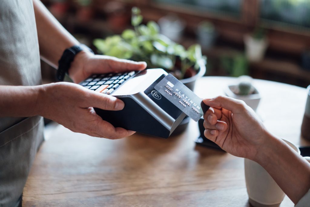 Close up of a woman's hand paying bill with credit card in a cafe