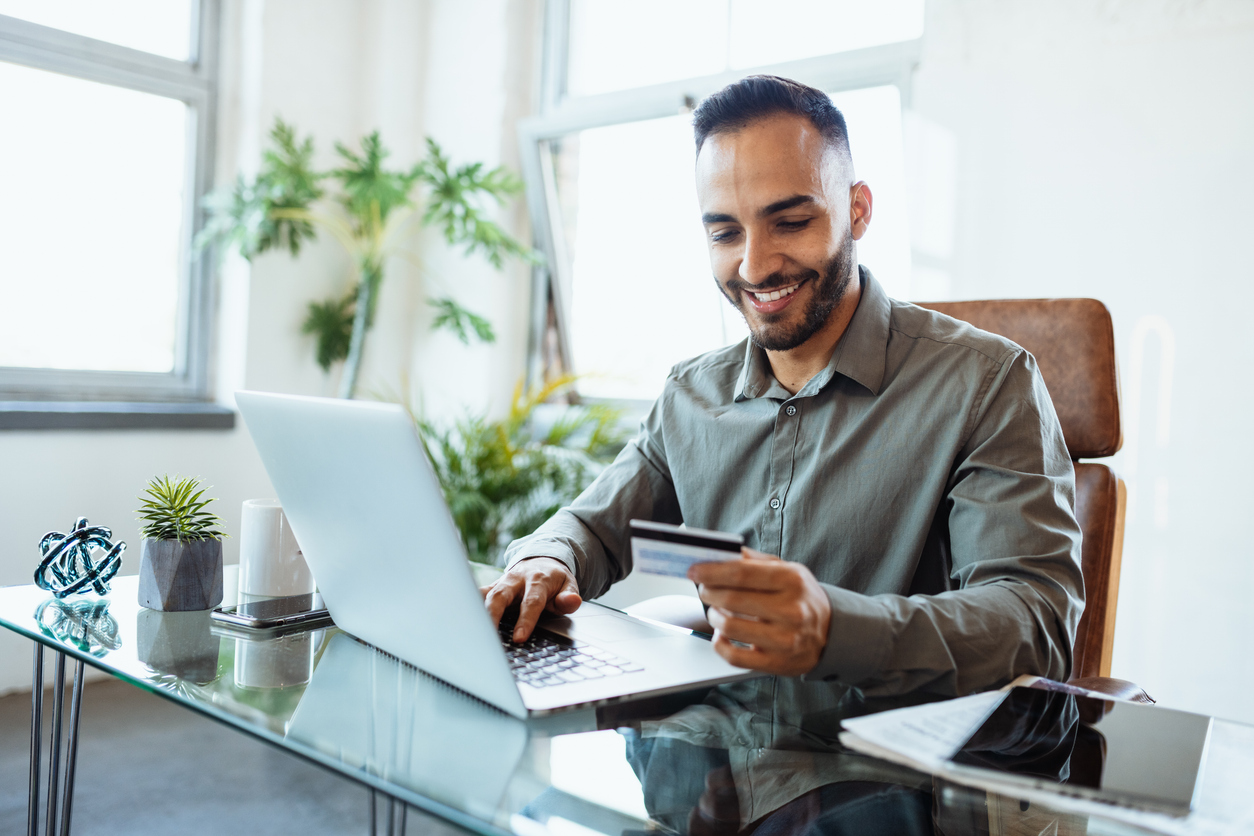 Seated in his office, a businessman wears a smile as he utilizes ACH payments for swift and efficient payment processing.